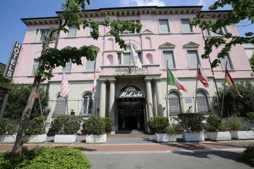 ein rosafarbenes Gebäude mit Flaggen davor in der Unterkunft Mokinba Hotels Montebianco in Mailand