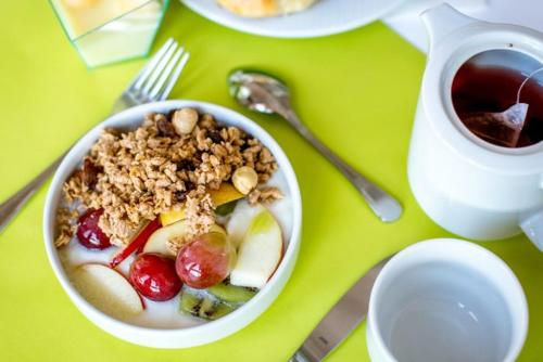 a bowl of cereal with fruit and nuts next to a cup of tea at Penzion Forman in Rožnov pod Radhoštěm