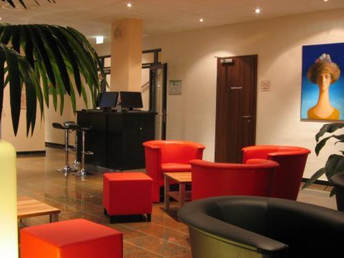 a waiting room with red chairs and a desk at Grand Hotel Dream Main City Center in Frankfurt