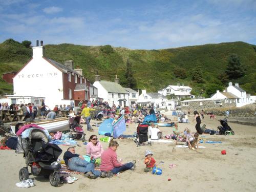 a group of people sitting on the beach at Swyn-Y-Mor in Morfa Nefyn