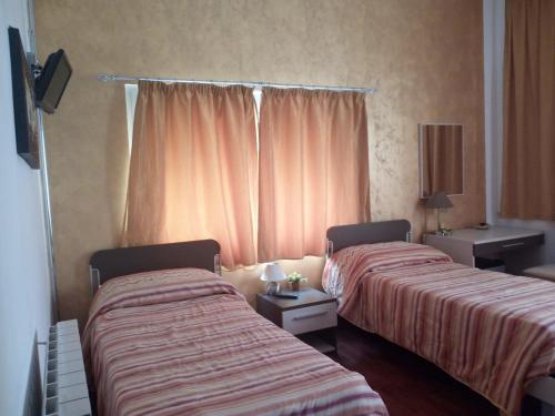 two beds in a hotel room with pink curtains at Eurelios in Adrano