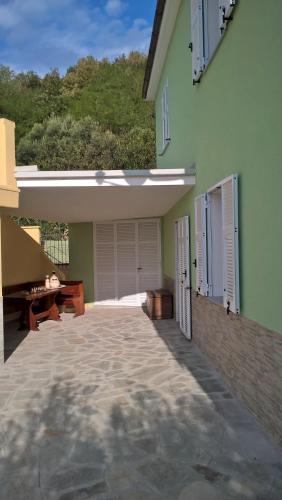 a green house with a patio and a garage at Casetta delle Fate , sport e natura in Noli