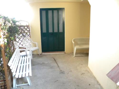 a porch with two white benches and a green door at Casetta delle Fate , sport e natura in Noli