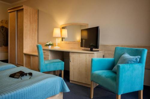 a hotel room with a bed and a desk with a television at Hotel La Siesta & Medical Spa in Jastrzębia Góra