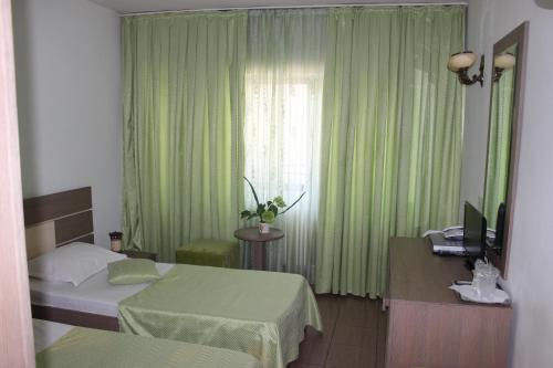 a bedroom with two beds and a window with green curtains at Hotel Ciucas in Vălenii de Munte
