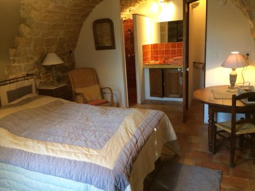 a bedroom with a bed and a table in a room at L'Oustaou de Rose in Bonnieux