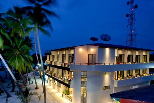 a building on the beach with palm trees at night at Kaani Beach Hotel in Maafushi