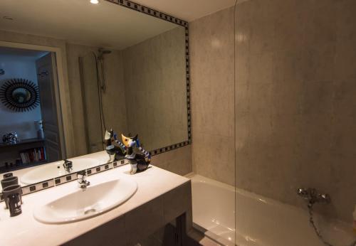 a bathroom with a sink and a mirror and a tub at Le Parc Pointe Croisette in Cannes