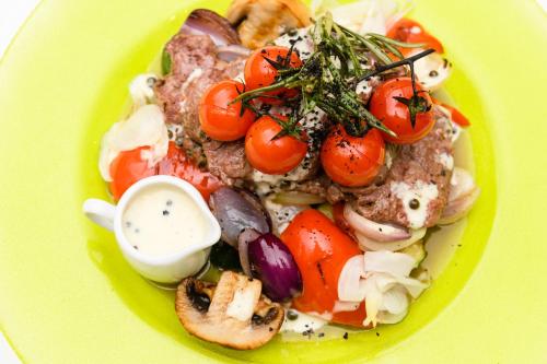 a yellow plate of food with tomatoes and mushrooms at Hotel Sitarska in Biłgoraj