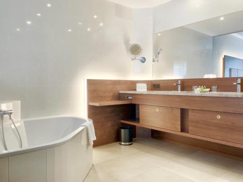 a bathroom with a tub and a large mirror at Schlosspark Mauerbach - Adults only in Mauerbach