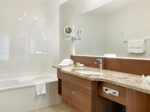 a bathroom with a sink and a tub and a mirror at Schlosspark Mauerbach - Adults only in Mauerbach