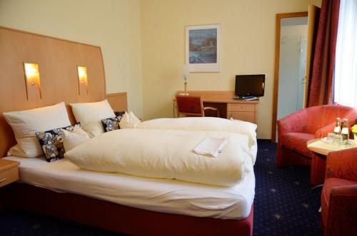 a hotel room with a large bed and a chair at Tannenheim in Boppard