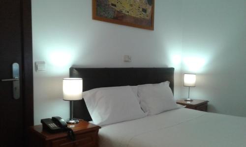 a bedroom with a bed with two lamps and a phone at Hotel Tic Tac in Bragança