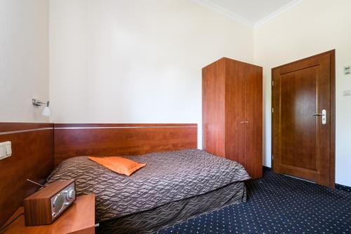 a small bedroom with a bed and a wooden cabinet at Hotel Sitarska in Biłgoraj