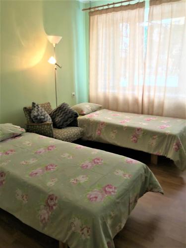 a bedroom with two beds and a chair and a window at LM Uus Külaliskorter in Põlva