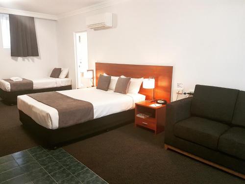 a hotel room with a bed and a couch at Mid City Motor Inn Singleton in Singleton