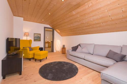 a living room with a gray couch and yellow chairs at GIRBL bio APARTMENTS - Haus Girbl in Strobl