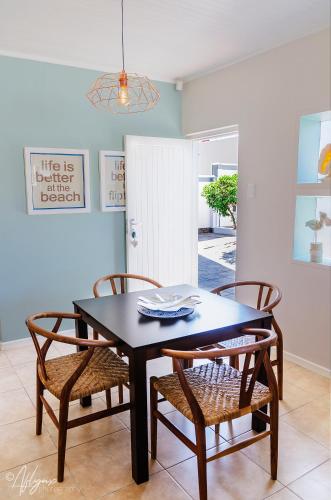 a dining room with a black table and chairs at Mylas Cottage in Swakopmund
