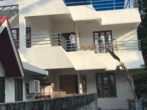 a man standing on the balcony of a white house at Angelann Homestay in Cochin