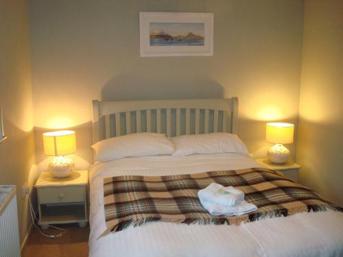 - une chambre avec un grand lit et deux lampes dans l'établissement Dunvegan Castle Laundry Cottage, à Dunvegan