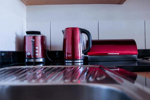 two red coffee cups sitting on top of a kitchen counter at Manhattan Suite-Canal Walk Mall in Cape Town