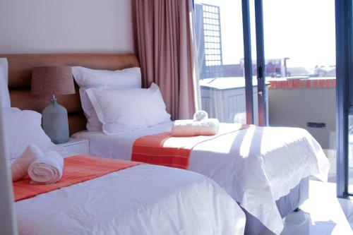 a hotel room with two beds and a window at Manhattan Suite-Canal Walk Mall in Cape Town