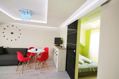 ein kleines Wohnzimmer mit einem Tisch und roten Stühlen in der Unterkunft Szafir in Kuźnica