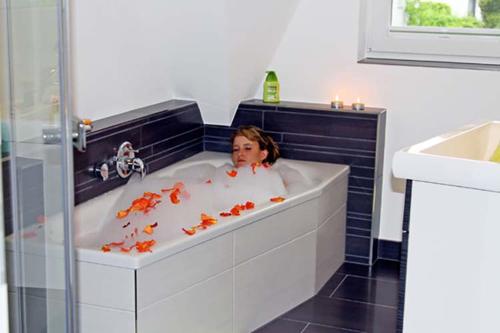 a woman in a bath tub with fish in it at Idylle unterm Reet - Reetdachhäuser am Walde in Trassenheide