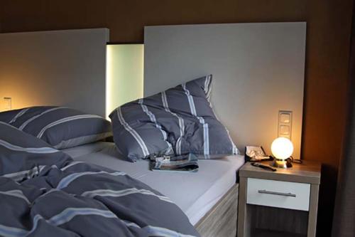 Una cama con almohadas azules y una mesa con lámpara. en Idylle unterm Reet - Reetdachhäuser am Walde, en Trassenheide