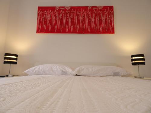 a bed with two pillows and a red painting on the wall at Museum House in Funchal