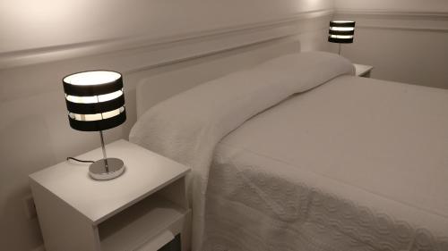 a white bedroom with a bed and a nightstand with two lamps at Museum House in Funchal