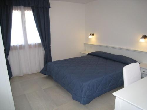 ein Schlafzimmer mit einem blauen Bett und einem Fenster in der Unterkunft Sillia Appartamenti in Pinzolo
