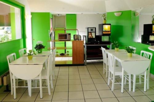 a kitchen with green walls and white tables and chairs at Lemon Hotel in Le Coteau