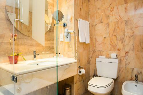 a bathroom with a sink and a toilet and a mirror at Hotel Pestana Cascais Ocean & Conference Aparthotel in Cascais