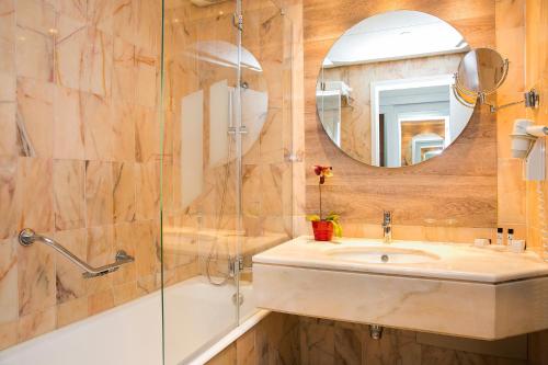 um banheiro com uma pia, um chuveiro e um espelho em Hotel Pestana Cascais Ocean & Conference Aparthotel em Cascais