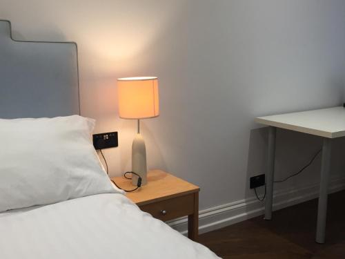 倫敦的住宿－Lexham Gardens Lodge 5，一间卧室配有一张床和一张桌子上的台灯