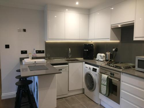a kitchen with white cabinets and a washing machine at Lexham Gardens Lodge 5 in London