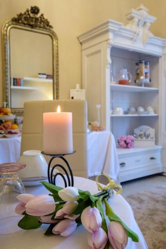 a candle sitting on a table with flowers and a candle at Your House Rooms in Genova
