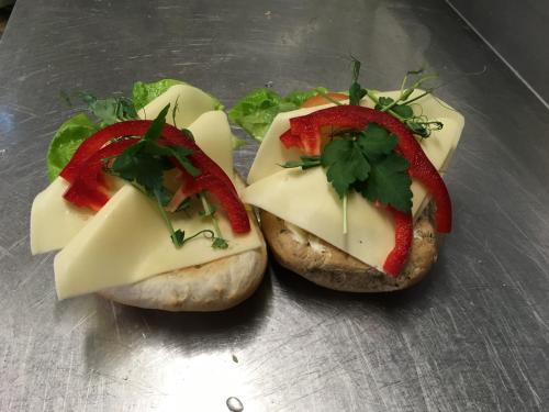 duas sanduíches com queijo e legumes num prato em Nordby Hotell em Lervik