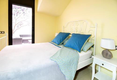a bedroom with a white bed with blue pillows at Heart of Sitges in Sitges