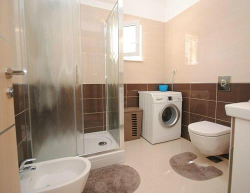 a bathroom with a shower toilet and a washing machine at Villa Guliver in Slatine