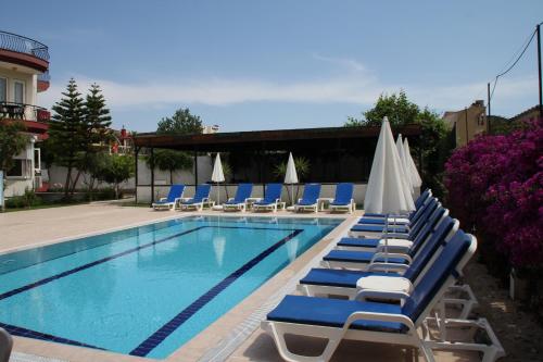 a swimming pool with lounge chairs and umbrellas at Minta Apart Hotel in Kemer
