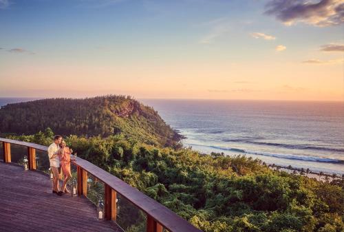 a man and woman standing on a boardwalk overlooking the ocean at Palm Hotel & Spa in Petite Île