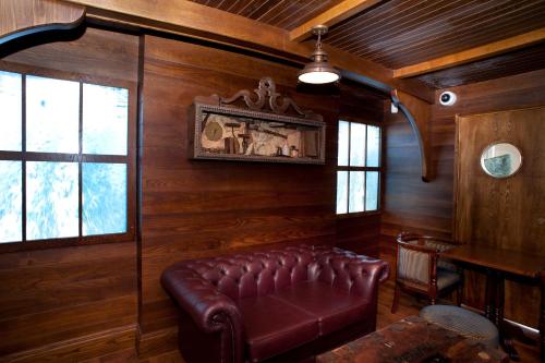 - un canapé en cuir dans une chambre dotée de murs en bois dans l'établissement Cabot Court Hotel Wetherspoon, à Weston-super-Mare