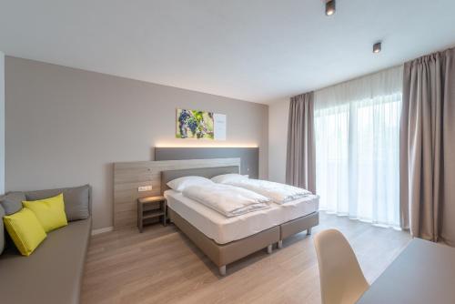 a white bedroom with a bed and a couch at Vineus Tramin in Termeno