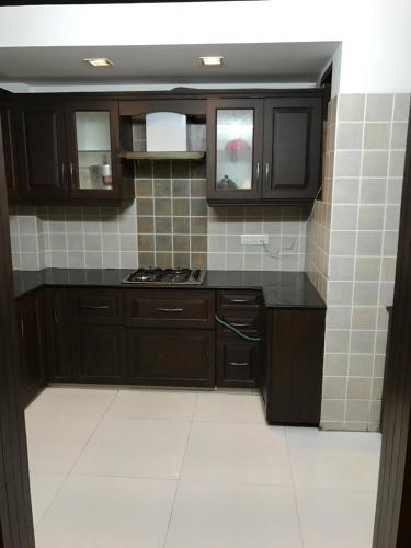 a kitchen with brown cabinets and a tile wall at Spacious 3bhk apartment! in New Delhi