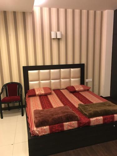 ein Schlafzimmer mit einem Bett und einem roten Stuhl in der Unterkunft Spacious 3bhk apartment! in Neu-Delhi