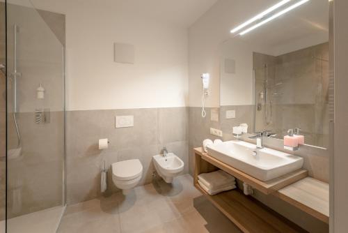 a bathroom with a sink and a toilet and a shower at Vineus Tramin in Termeno