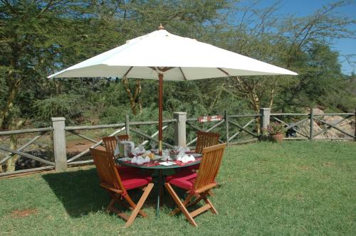 a table with an umbrella in the grass at Maneaters in Tsavo