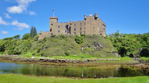 een kasteel bovenop een heuvel naast een rivier bij Dunvegan Castle Laundry Cottage in Dunvegan